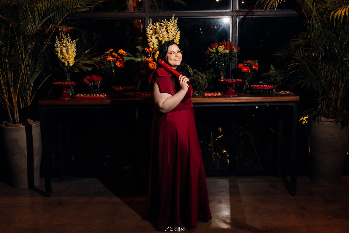 Foto posada de corpo inteiro da Carolina diante da mesa decorada da festa.