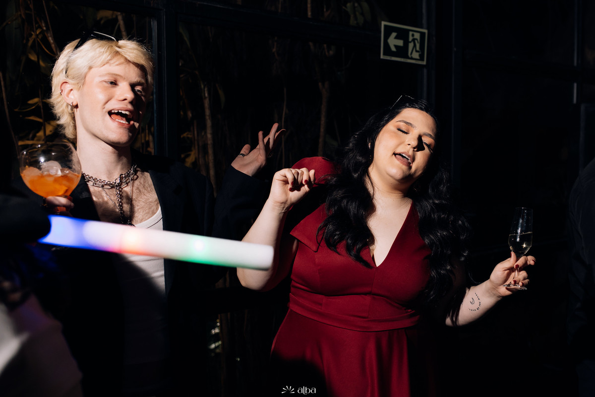 Carolina dançando com amigos e luzes de festa durante a formatura no Bierdron.