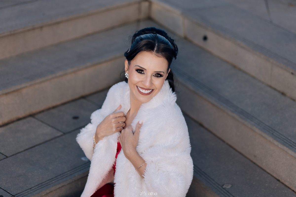 Retrato de Lígia nas escadas com estola branca, sorriso aberto.