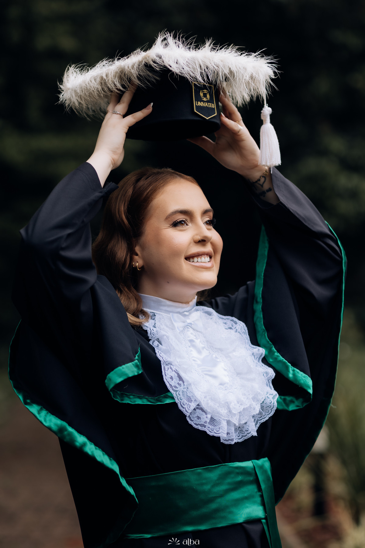 Formanda levantando o capelo com plumas brancas no ensaio de toga da Univates – Alba Estúdio, Lajeado.