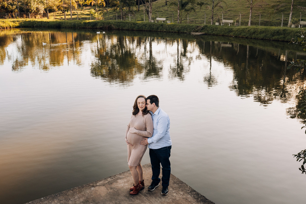 Casal à beira de lago, com reflexo da natureza na água, em ensaio gestante ao ar livre em Lajeado – fotografia por Alba Estúdio.