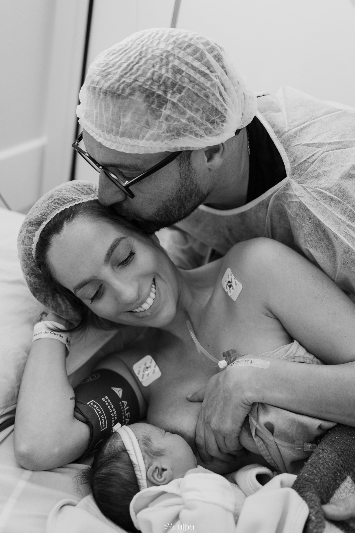 Papai beijando a mamãe enquanto ela amamenta a Amália no Hospital Bruno Born, em Lajeado/RS — registro do Alba Estúdio.