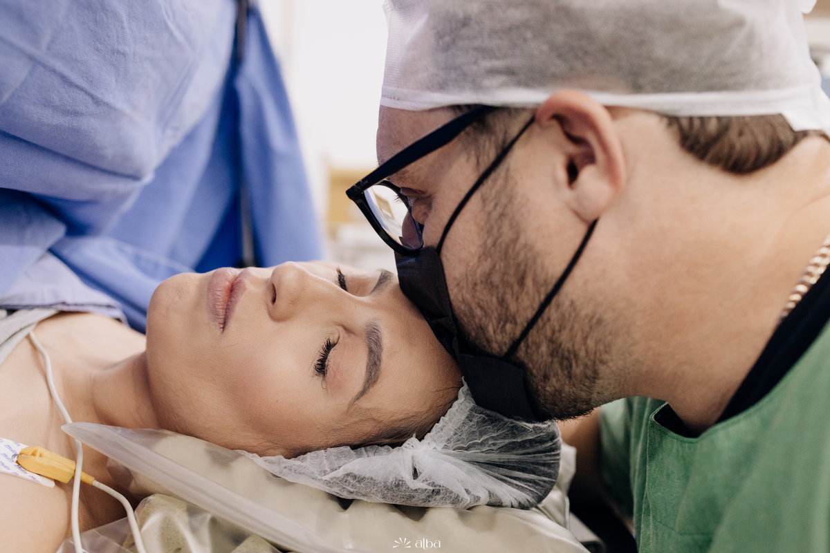 Pai beijando a testa da mãe na sala de parto do Hospital Bruno Born, em Lajeado/RS, antes do nascimento da Amália. Foto feita pelo Alba Estúdio.