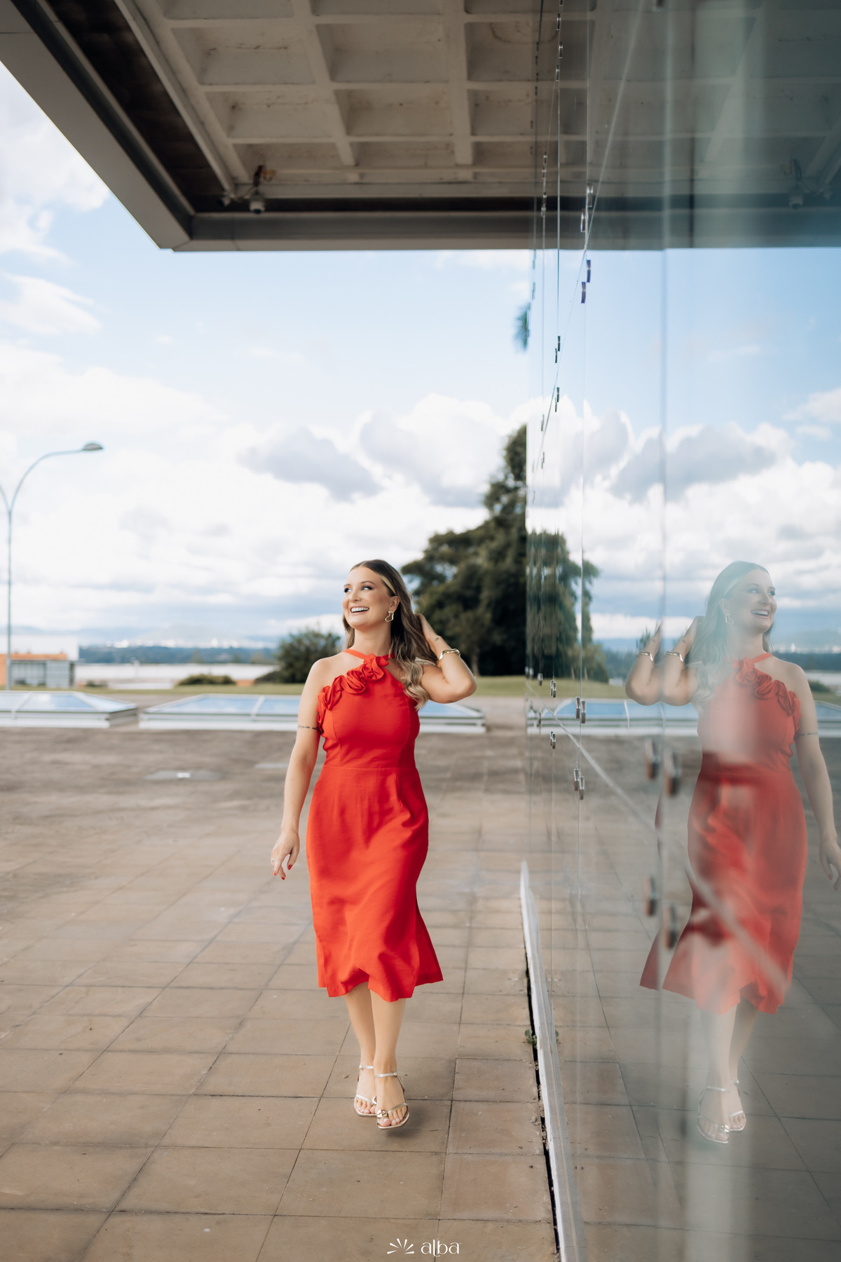 Ensaio de formatura da Rafaela na Univates, em Lajeado, com vestido vermelho e reflexo no vidro, fotografado pelo Alba Estúdio.