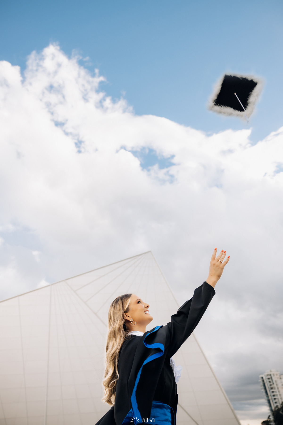 Formanda Rafaela jogando o capelo durante ensaio de formatura na Univates, em Lajeado, registrado pelo Alba Estúdio.