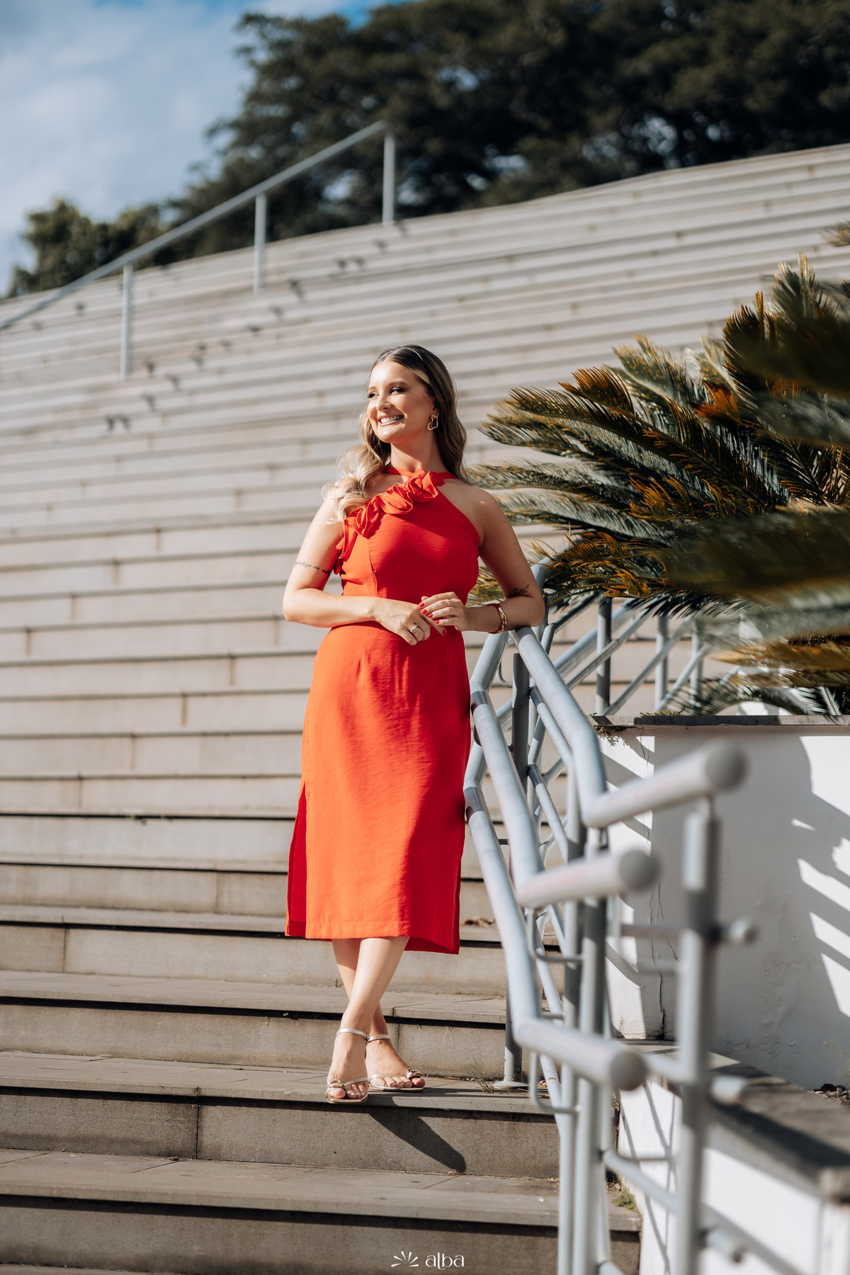 Foto de formatura da Rafaela na Univates, em Lajeado, usando vestido vermelho nas escadarias do campus, pelo Alba Estúdio.