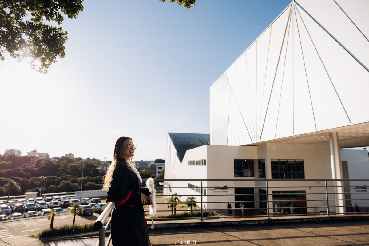 Milena em ensaio de formatura na Univates, em Lajeado, com a arquitetura do campus ao fundo, pelo Alba Estúdio.