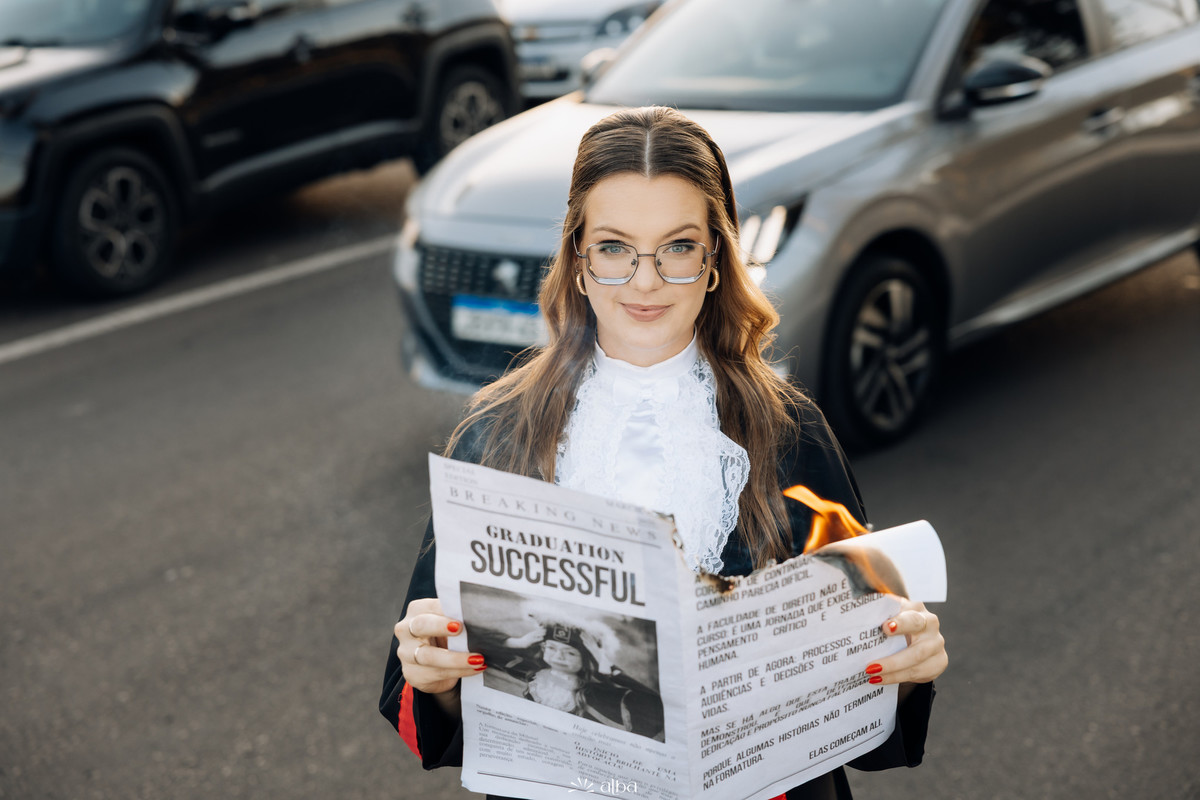 Retrato da Milena com jornal personalizado durante ensaio de formatura na Univates, em Lajeado, pelo Alba Estúdio.