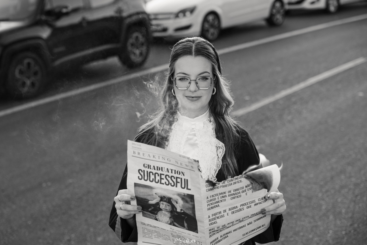 Milena em retrato de formatura na Univates, em Lajeado, com jornal personalizado em foto preto e branco pelo Alba Estúdio.