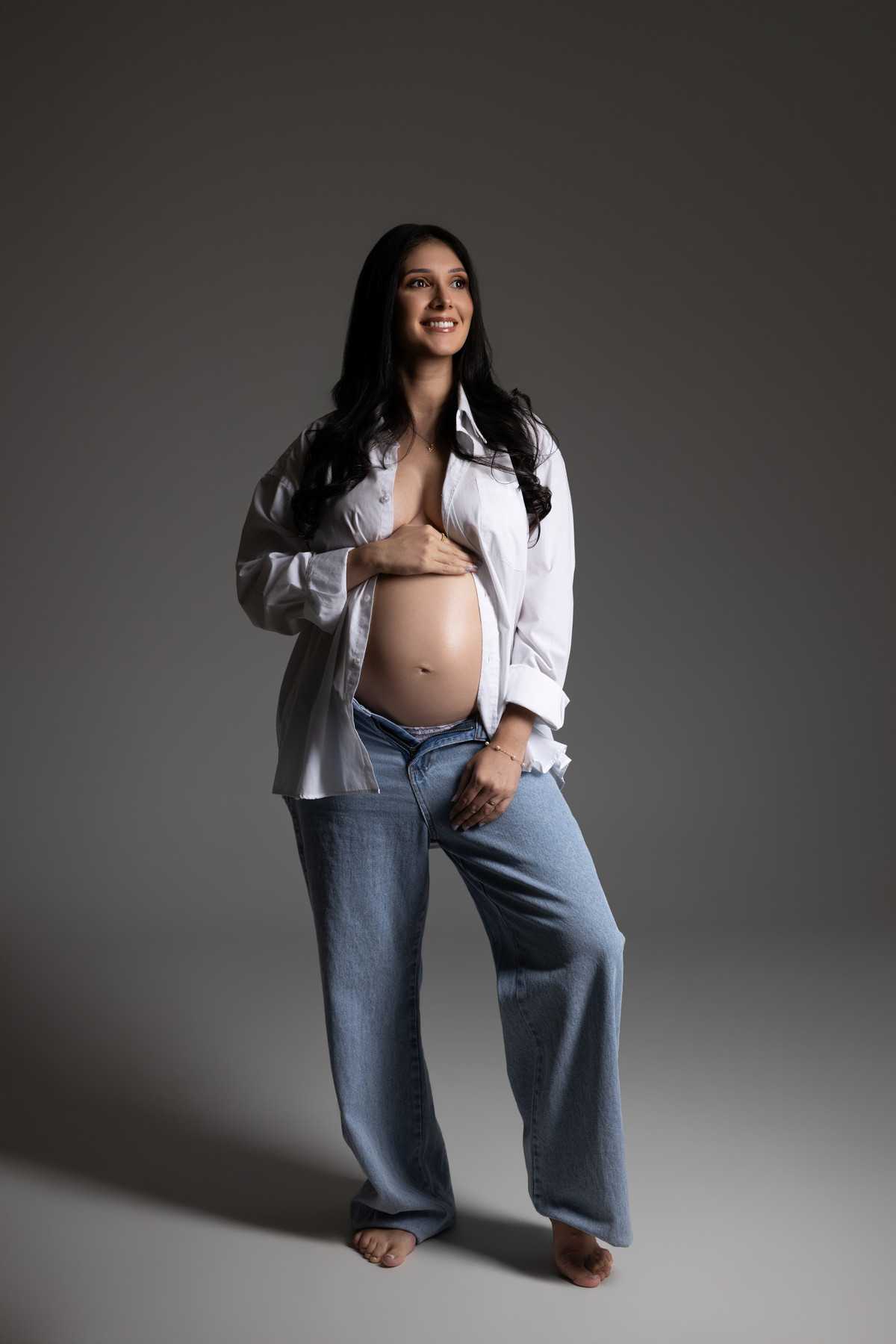 Ensaio gestante em estúdio com look casual de camisa branca e jeans, valorizando a beleza e a naturalidade da maternidade. Fotografia do Alba Estúdio em Lajeado, RS.
