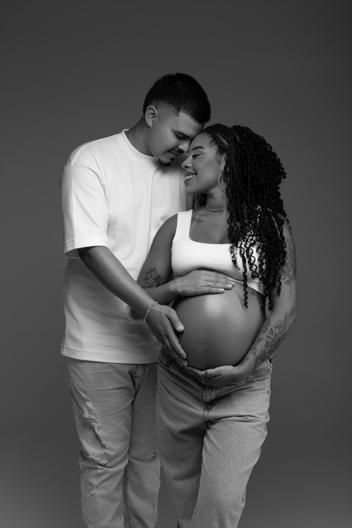 Retrato de casal durante ensaio gestante em estúdio, com composição em preto e branco e um momento delicado de carinho na espera por Maju. Fotografia do Alba Estúdio em Lajeado, RS.