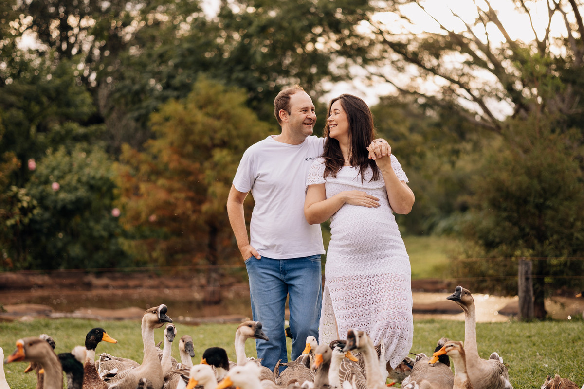 Casal gestante em ensaio externo divertido junto a patos e gansos | Fotografia criativa de gravidez pelo Alba Estúdio.