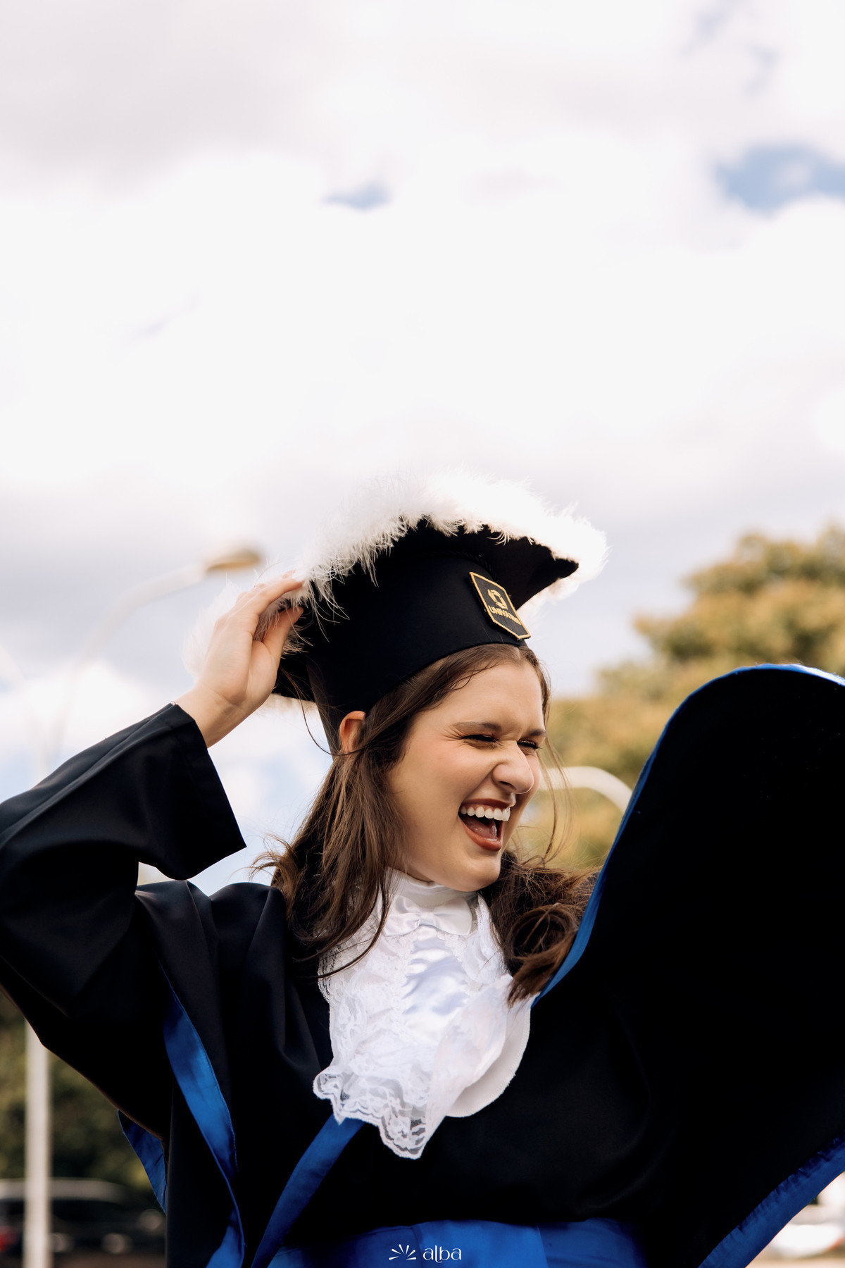 Formanda comemorando a conquista com toga e capelo em fotografia espontânea de formatura na Univates, em Lajeado RS.