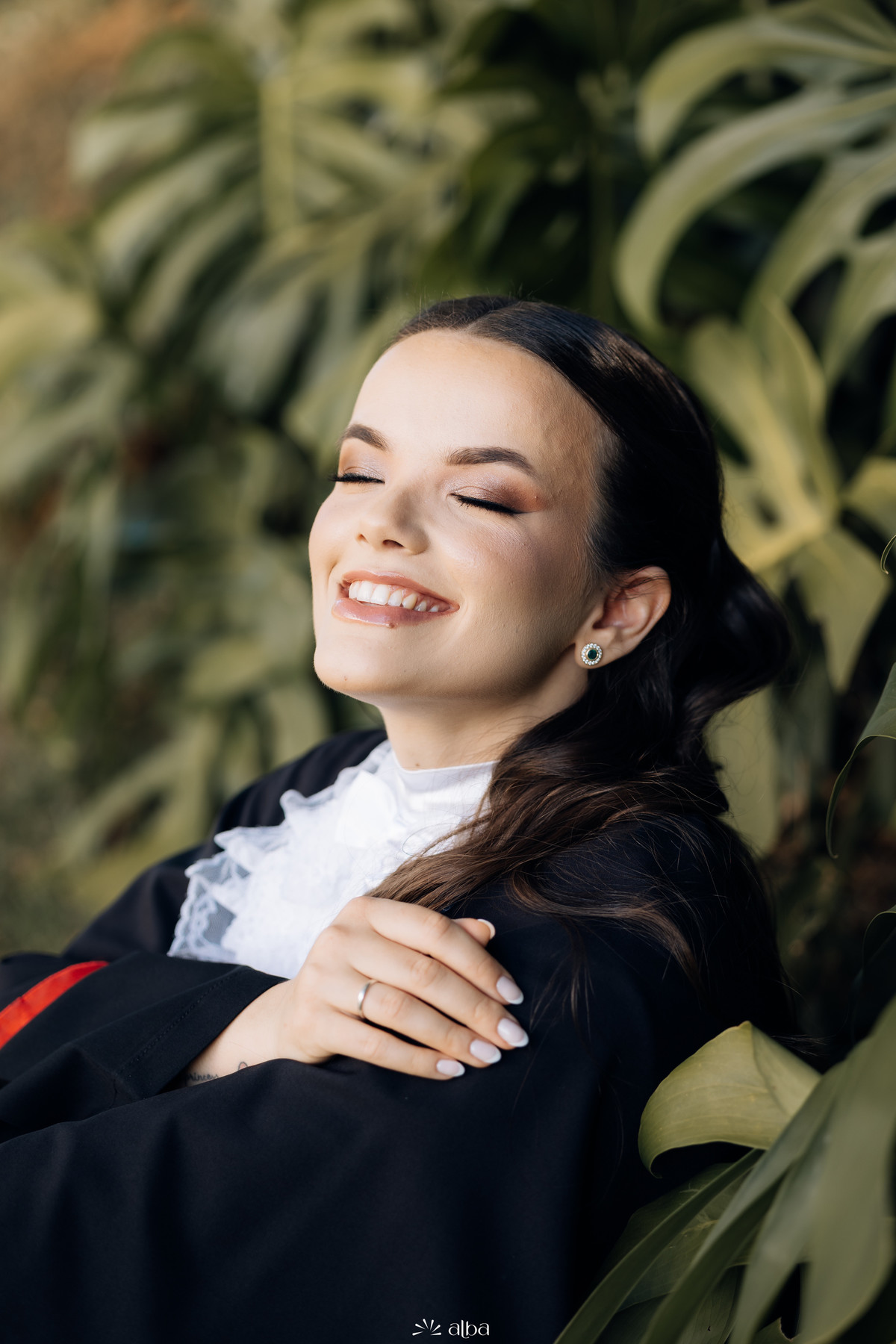 Retrato espontâneo de formanda sorrindo entre folhagens durante ensaio de formatura na Univates, em Lajeado RS.