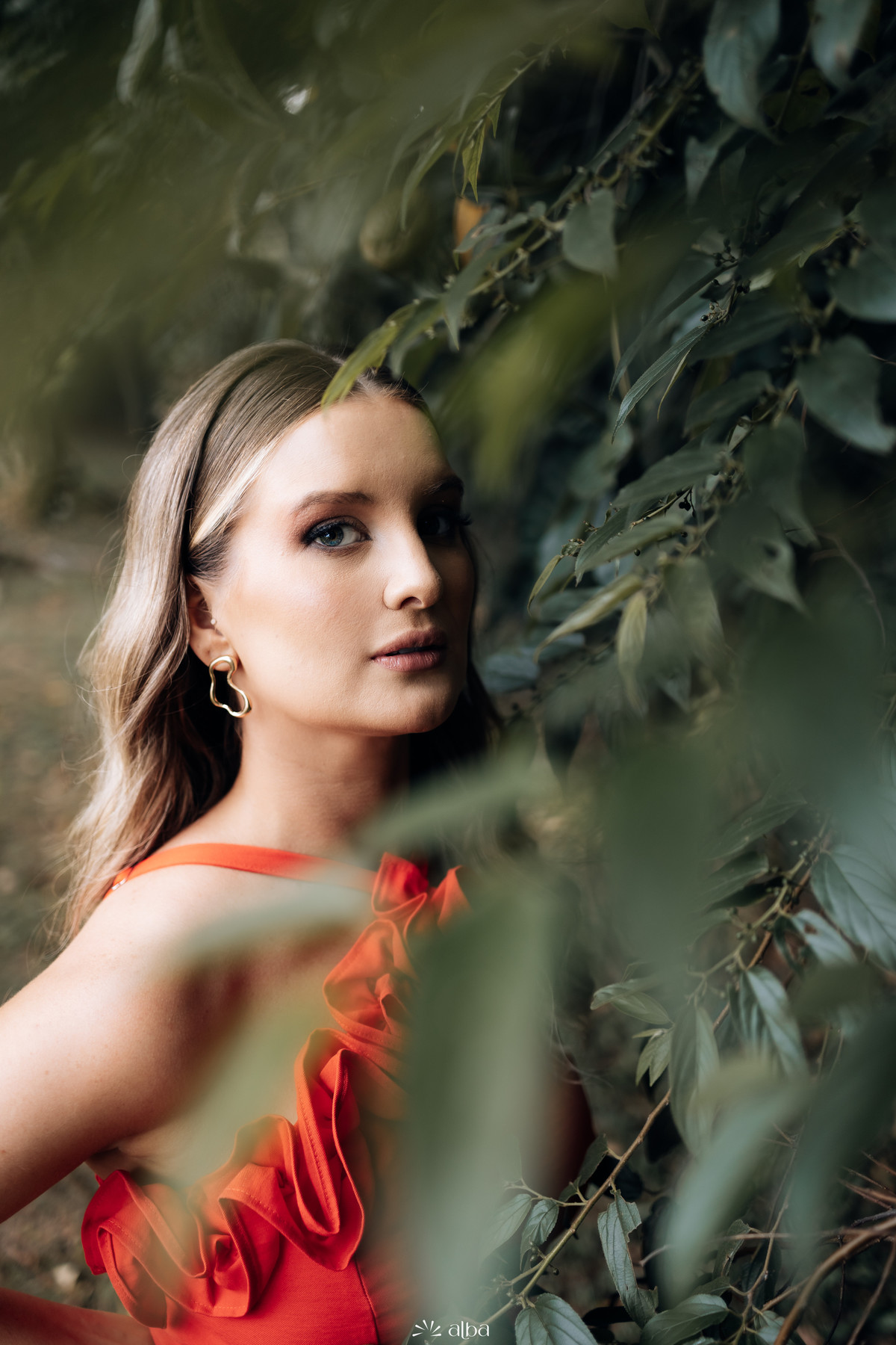 Retrato elegante de formanda com vestido vermelho entre folhagens durante ensaio de formatura em Lajeado RS | Fotografia Alba Estúdio.