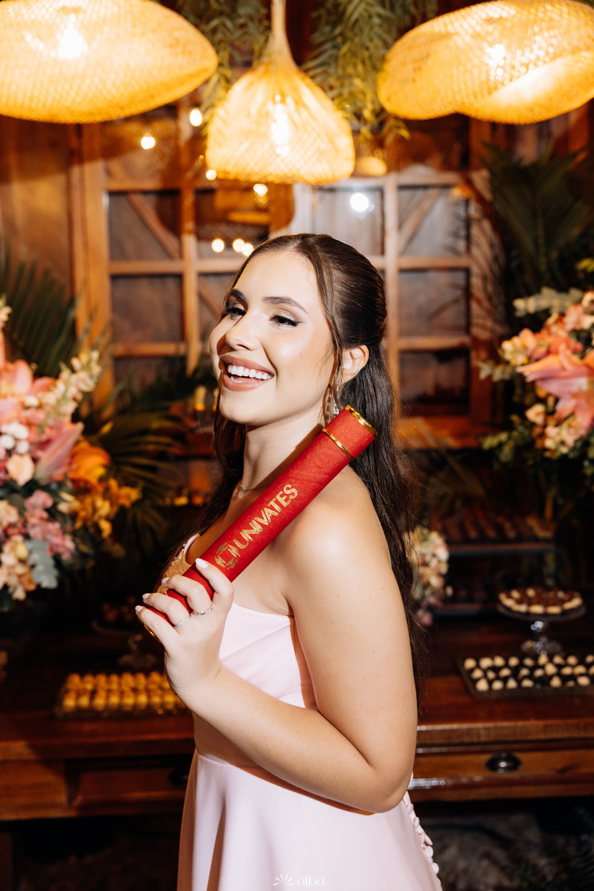 Formanda sorridente com diploma da Univates em retrato elegante na festa de formatura realizada na Casa Irmando.