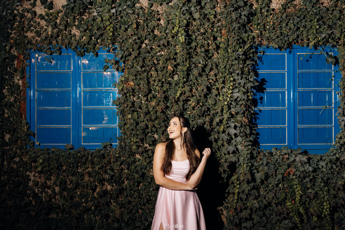 Ensaio noturno de Ana Pellini com vestido rosa junto às janelas azuis da Casa Irmando | Fotografia de formatura Alba Estúdio.