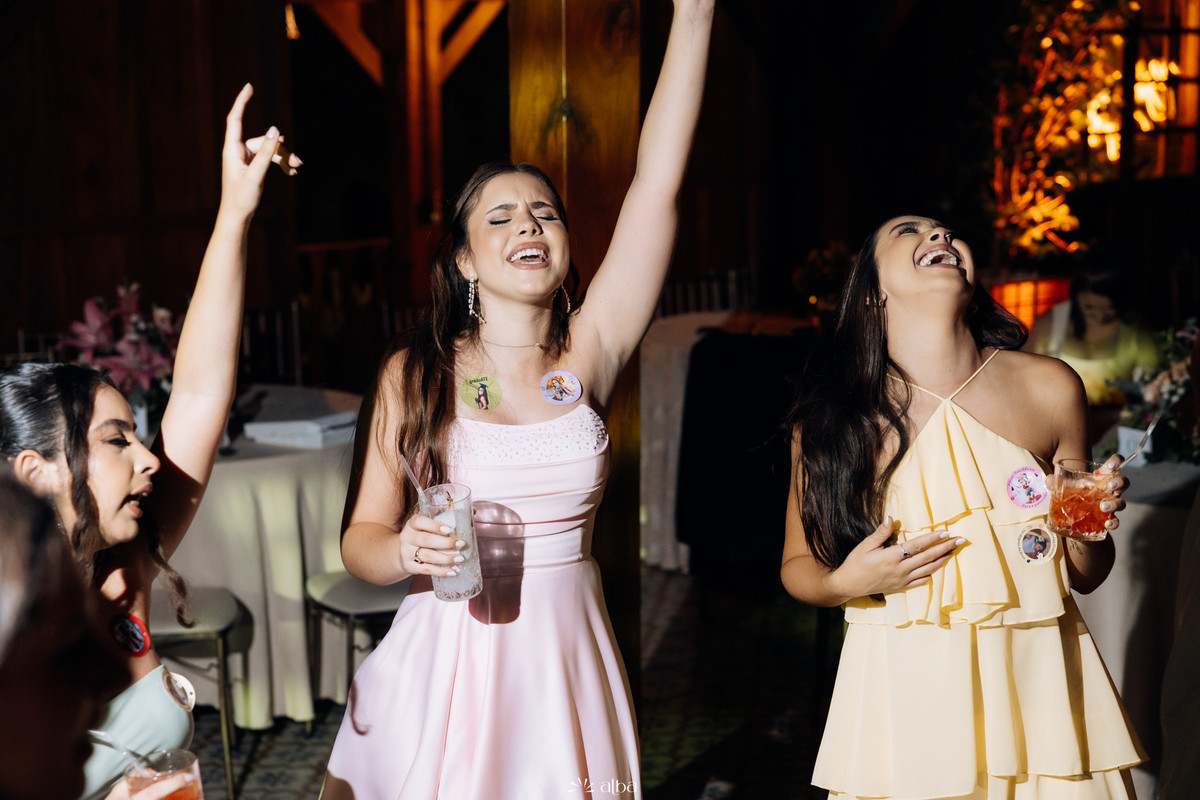Ana Pellini cantando e celebrando com uma amiga na pista de dança durante sua festa de formatura na Casa Irmando.
