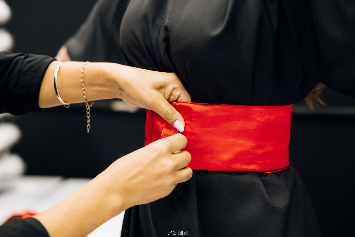 Ajuste da faixa vermelha na toga durante os preparativos para a colação de grau na Univates | Fotografia de formatura Alba Estúdio.