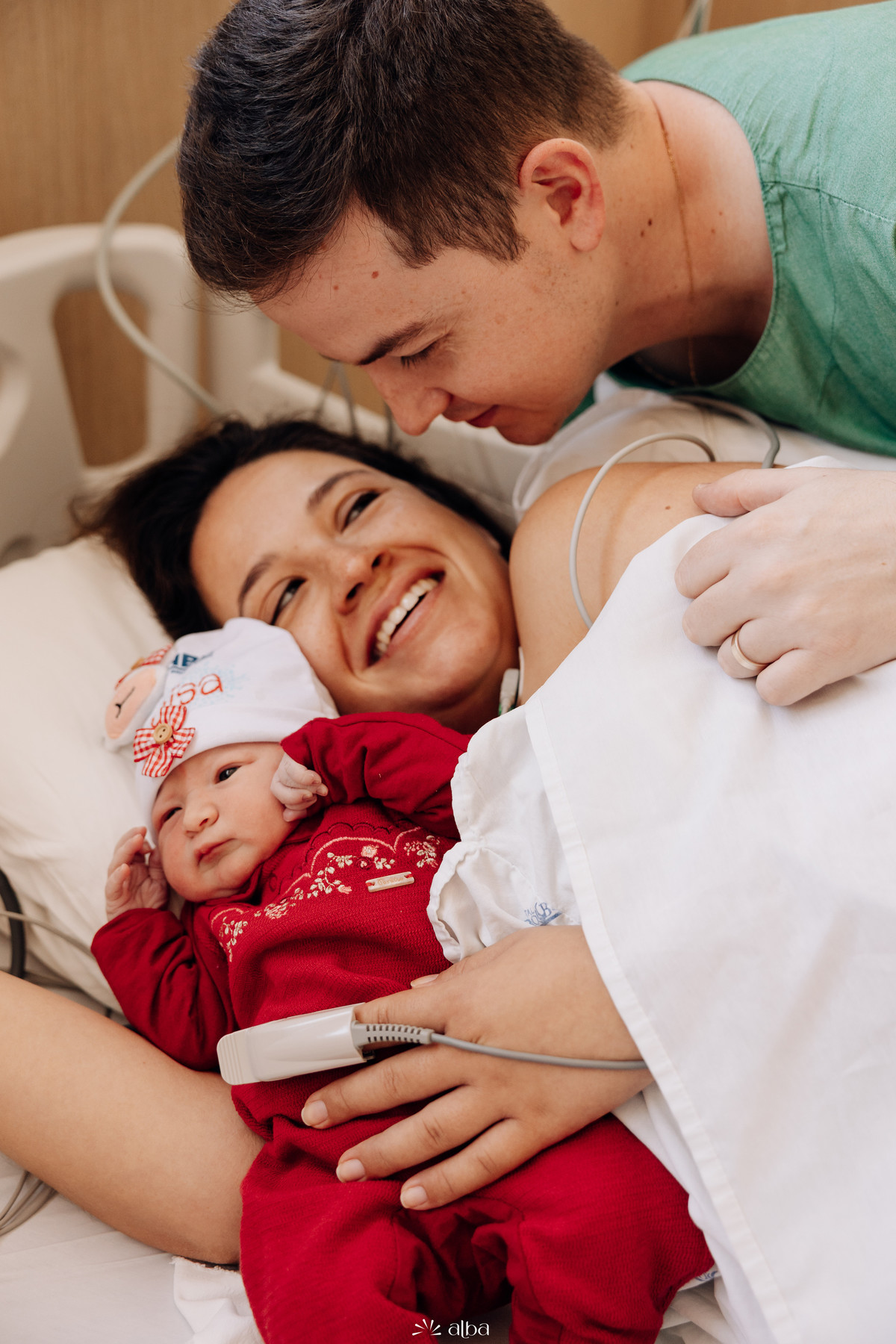 Pai, mãe e bebê reunidos no quarto após o nascimento no Hospital Bruno Born, em Lajeado. Fotografia afetiva de família por Alba Estúdio.