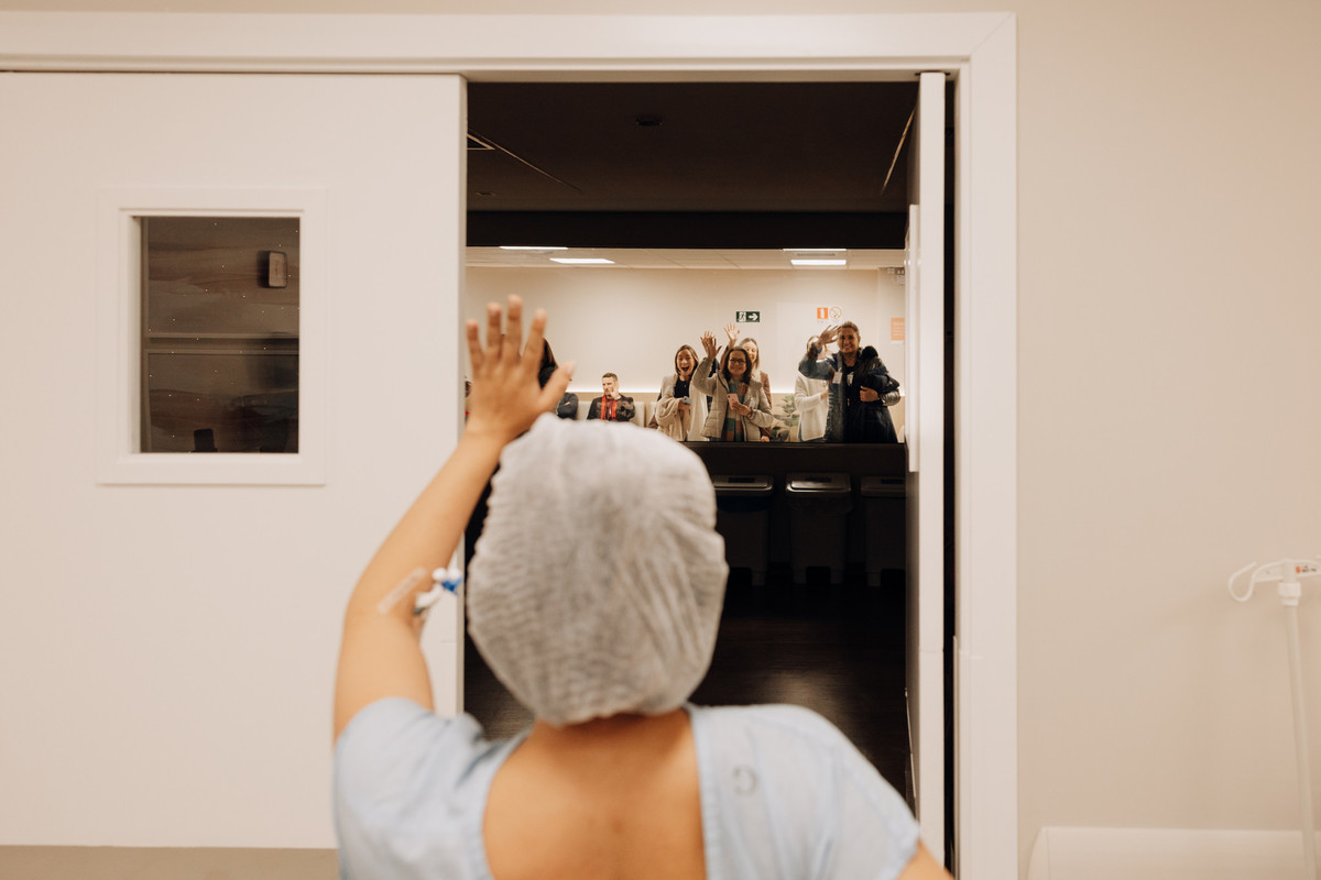 Mãe acena emocionada para os familiares após o parto no Hospital Bruno Born, em Lajeado. Registro espontâneo de nascimento por Alba Estúdio.