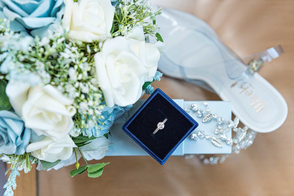 Casamento com a Débora e o Felipe mostrando as alianças, sapato e flores no casamento no Brás, São Paulo