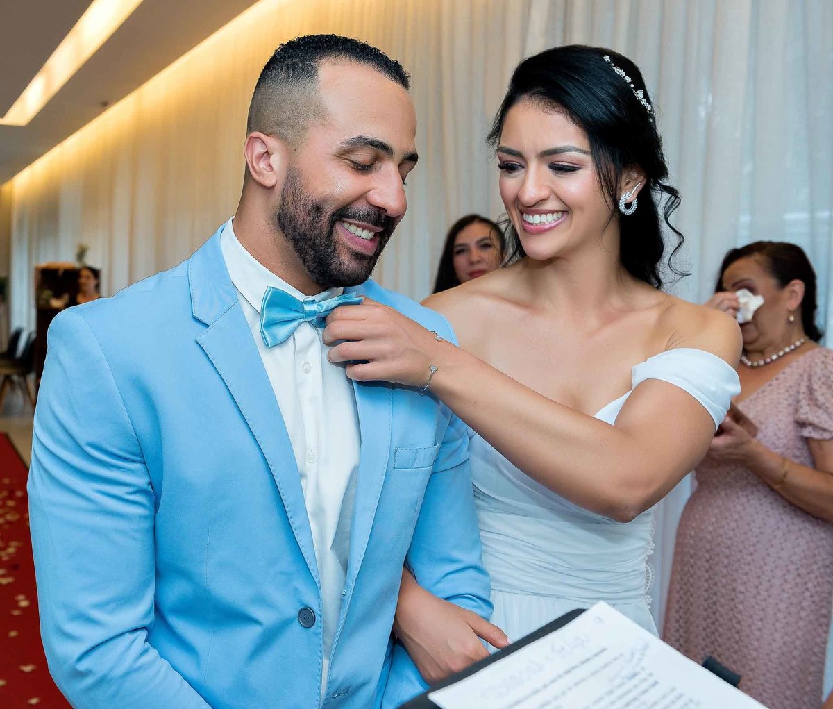 Cerimônia do casamento com a Débora arrumando a gravata do Felipe sorrindo muito no casamento no Brás, São Paulo