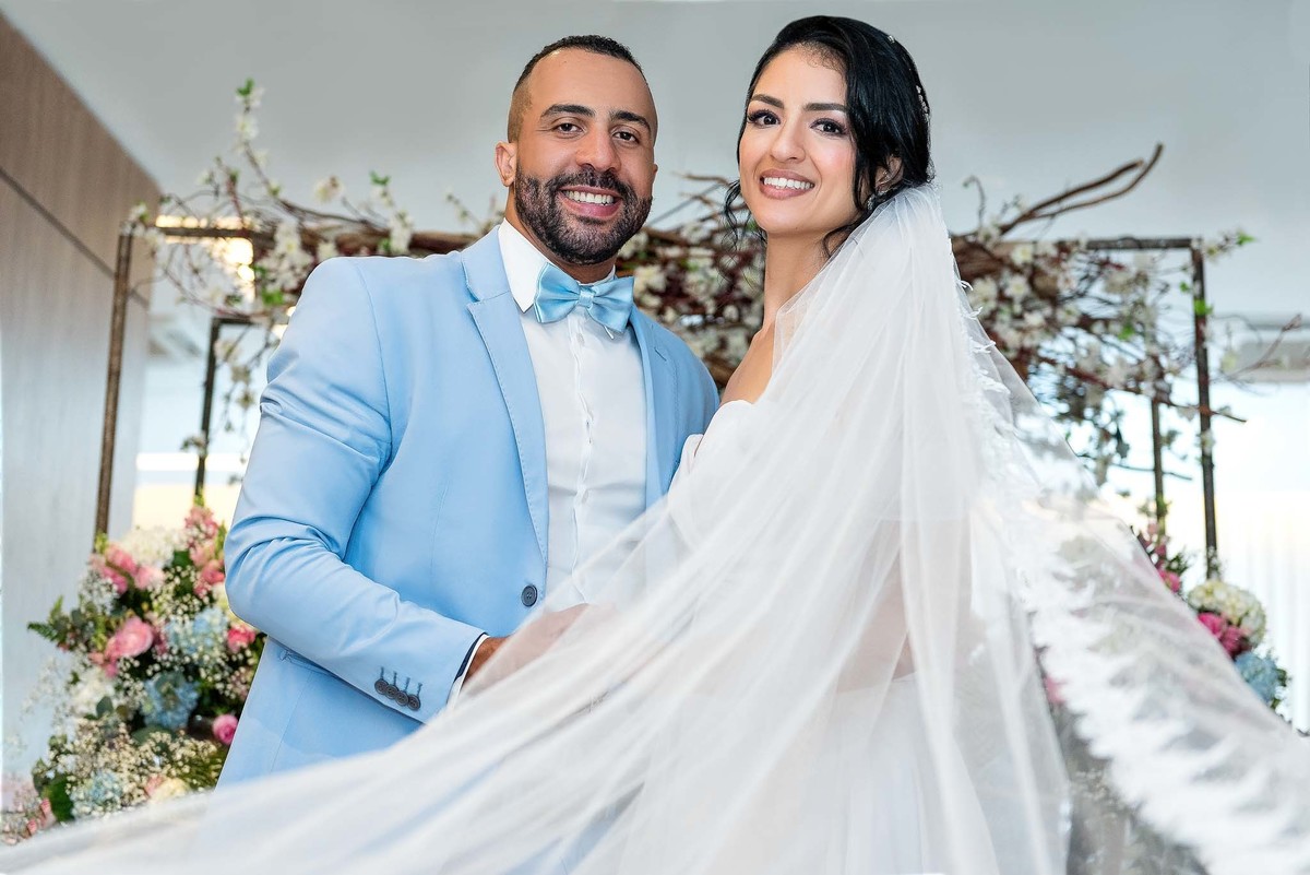 Cerimônia do casamento com a Débora e o Felipe sorrindo mostrando  uma parte do vestido no casamento no Brás, São Paulo