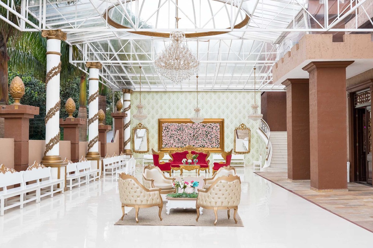 Decoração elegante de salão de festa, com mesas postas em tons de vermelho e branco, arranjos florais e lustres, mostrando o ambiente do Marilias Buffet