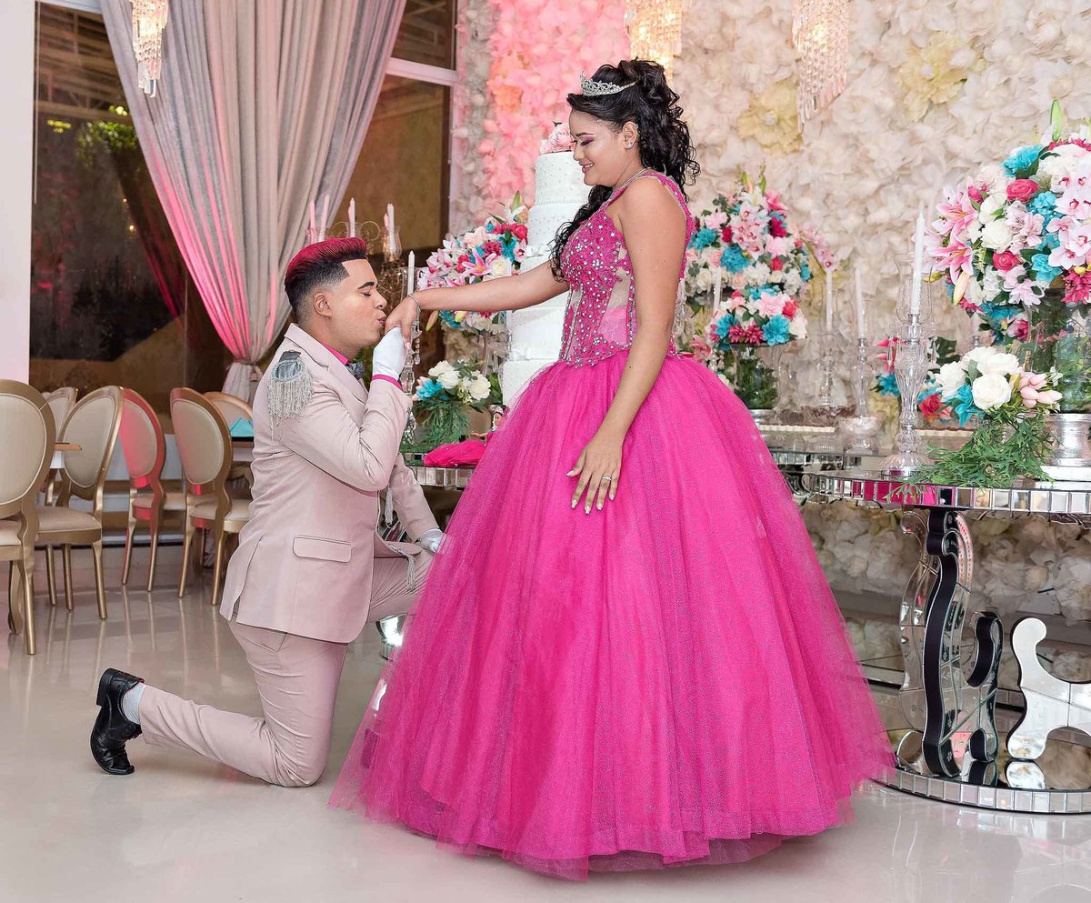 Príncipe se ajoelhando para Jamile durante o ensaio em um momento clássico da festa de 15 anos, com a debutante em seu vestido rosa choque