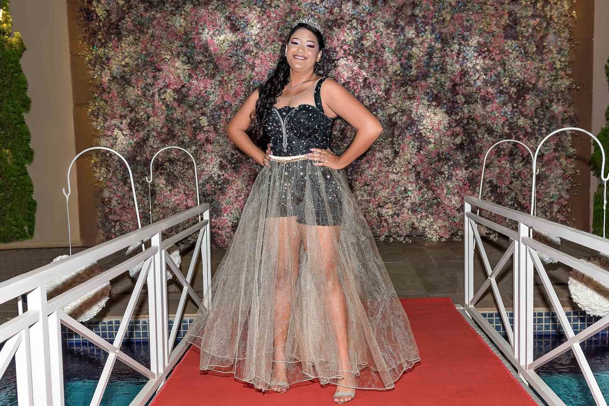 Jamile com um vestido de festa transparente e brilhante, posando em uma passarela, mostrando um segundo look