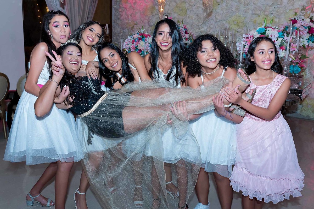 Jamile e suas amigas, vestidas de forma semelhante (algumas de branco e outras de rosa/lilás), deitadas no chão em um círculo, mostrando descontração