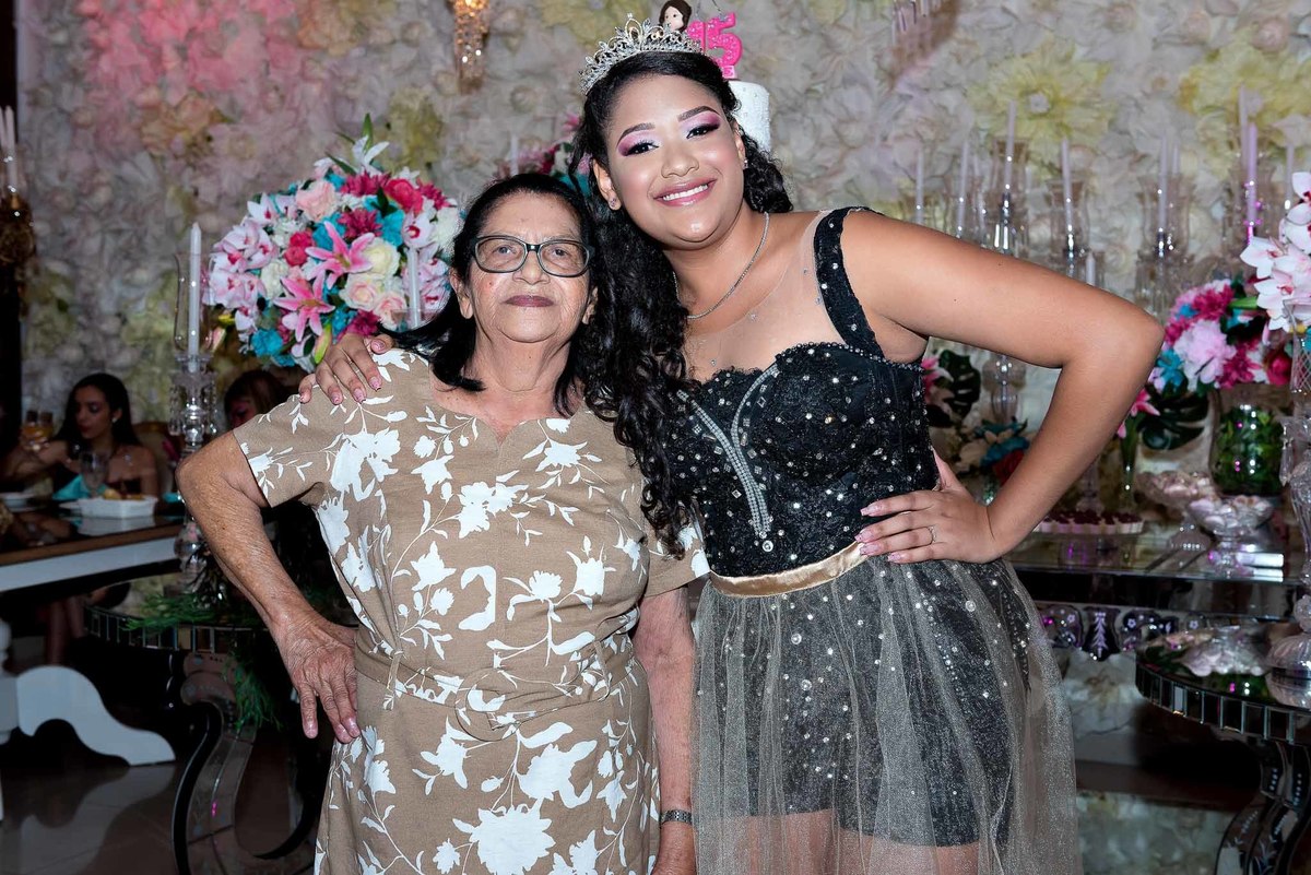 Jamile com a sua avó na festa, ambas sorrindo e com o braço em volta uma da outra, mostrando a amizade