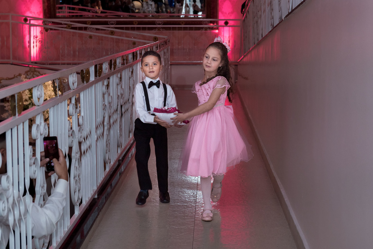 Jamile em um vestido rosa brilhante curto, dançando com energia na pista de dança, com iluminação de balada ao fundo