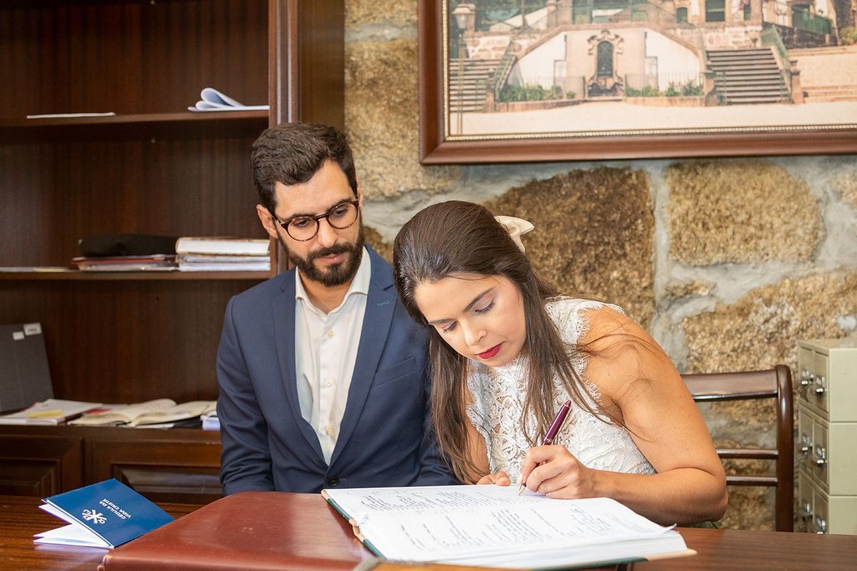 Os padrinhos do Tomás a assinarem os papeis do batismo