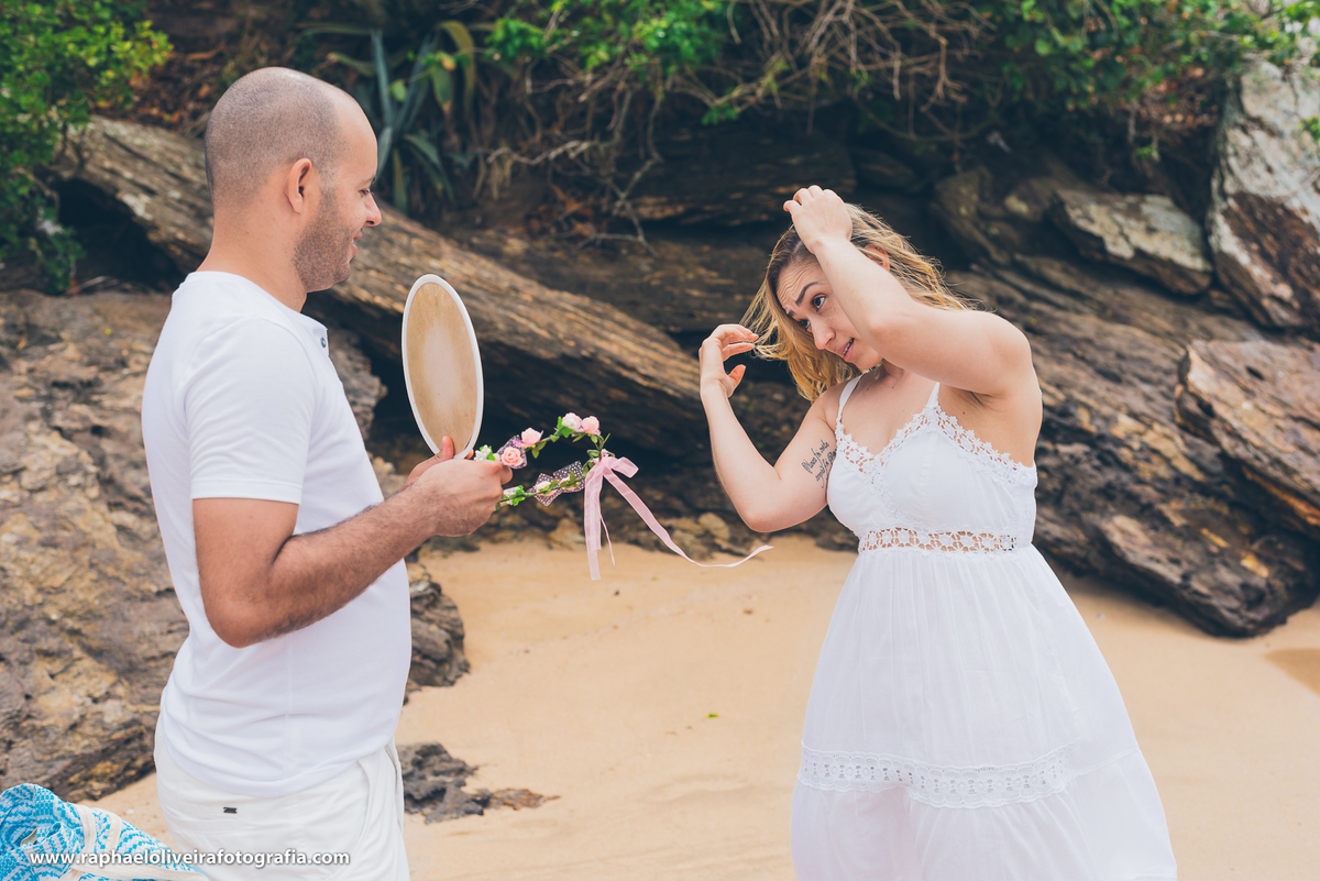 noivo segurando o espelho para noiva arrumar o cabelo durante a sessão fotográfica