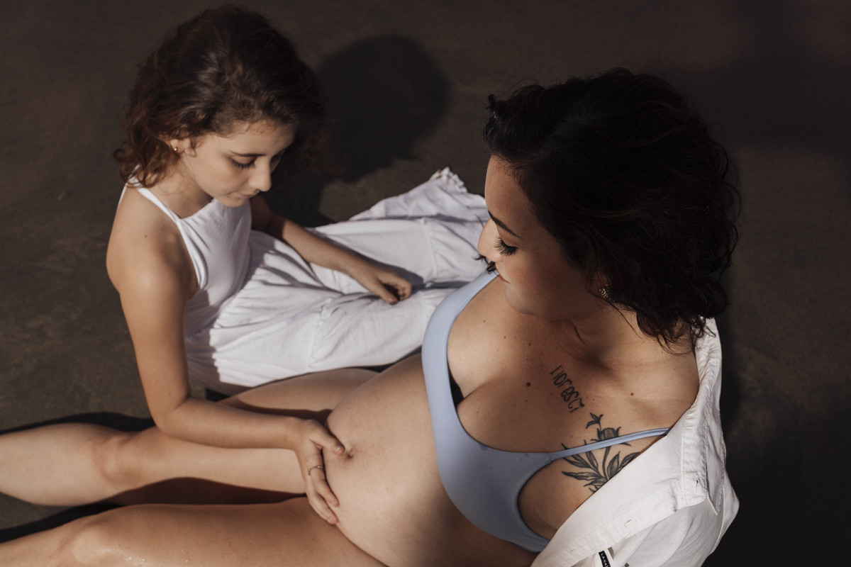 primeira filha colocando a mao na barriga da mae pra sentir o irmao