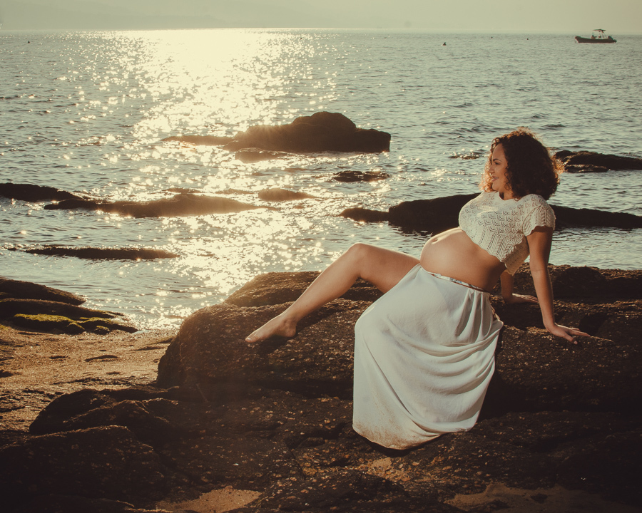 gestante sentada na pedra admirando o mar 