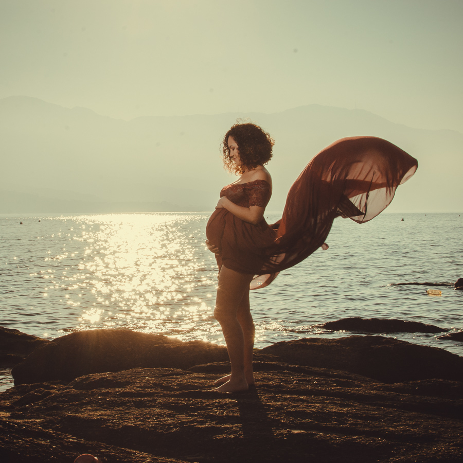 gestante na praia em cima da pedra olhando para a barriga Ilhabela