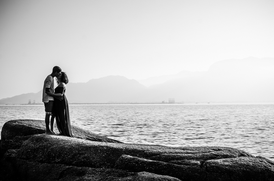 casal se beijando em cima da pedra com o fundo do mar 