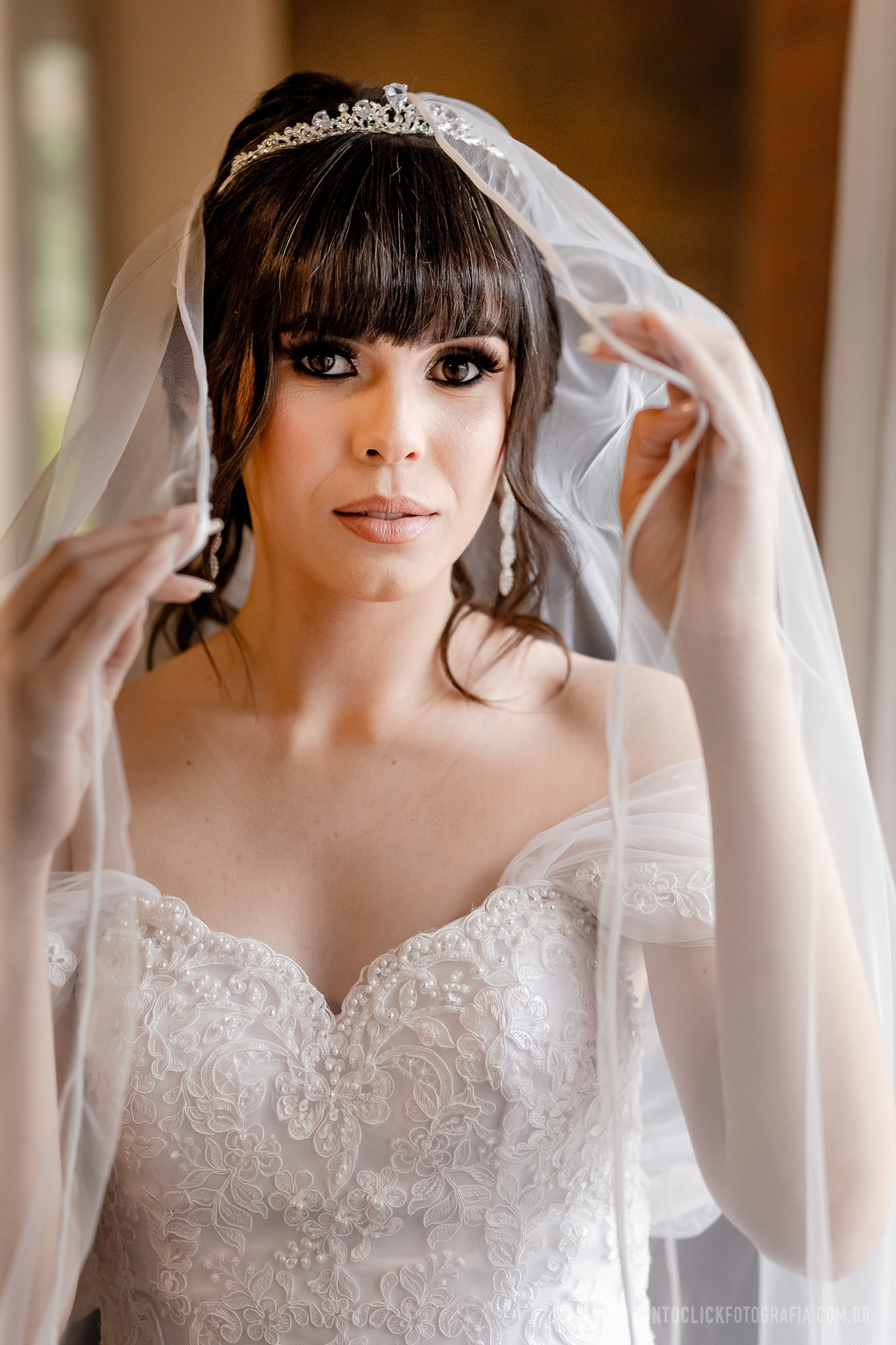 Noiva segurando o véu com as duas mãos olhando para câmera fotográfica 