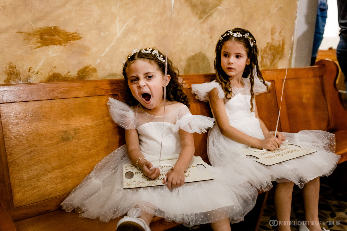 Daminhas de casamentos vestidas com vestidos de da minha sentada no banco da igreja católica no e vinha bocejando
