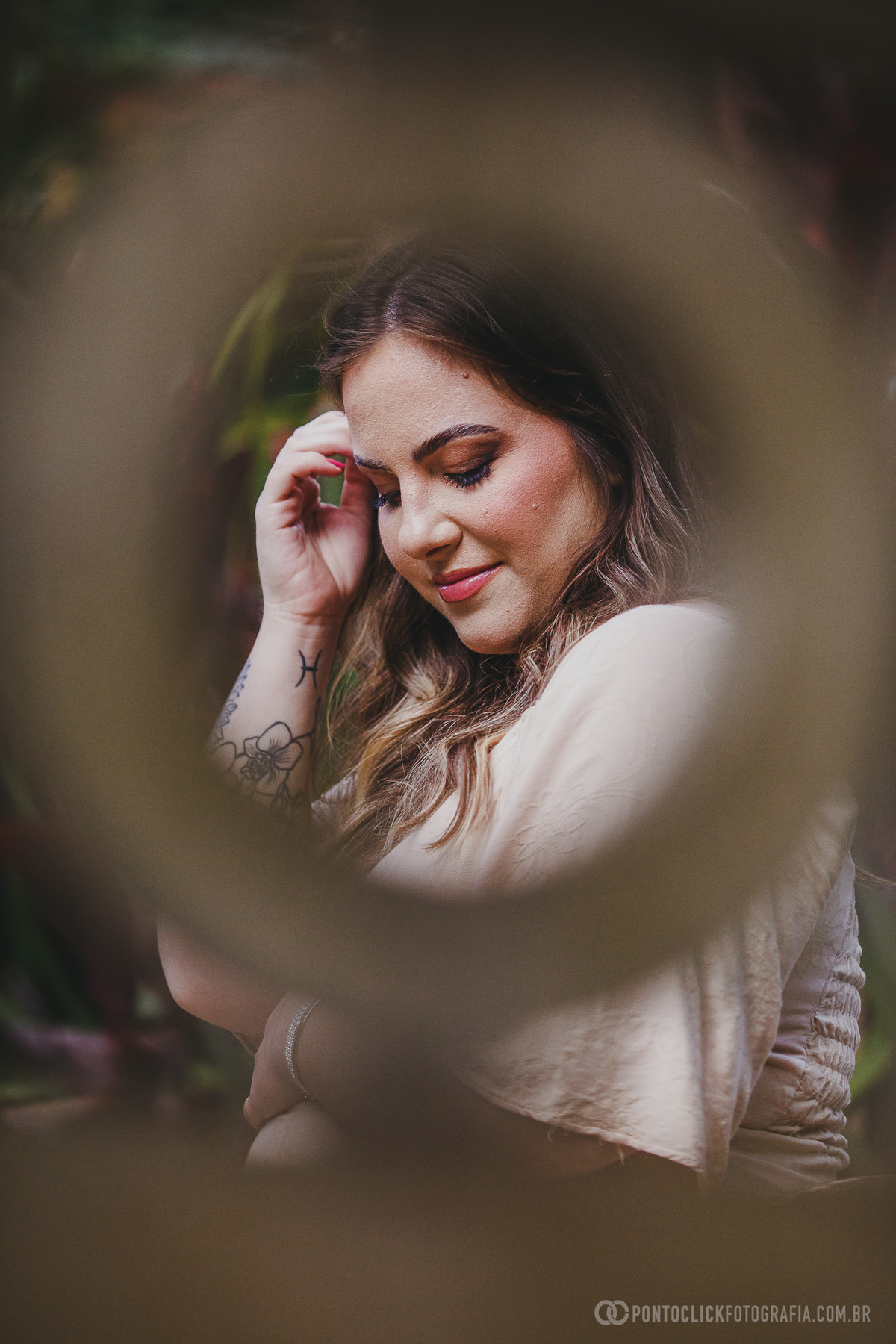 Enquadramento artístico de Fernanda com fundo desfocado, destacando seu sorriso suave e expressão contemplativa. Uma celebração da maternidade