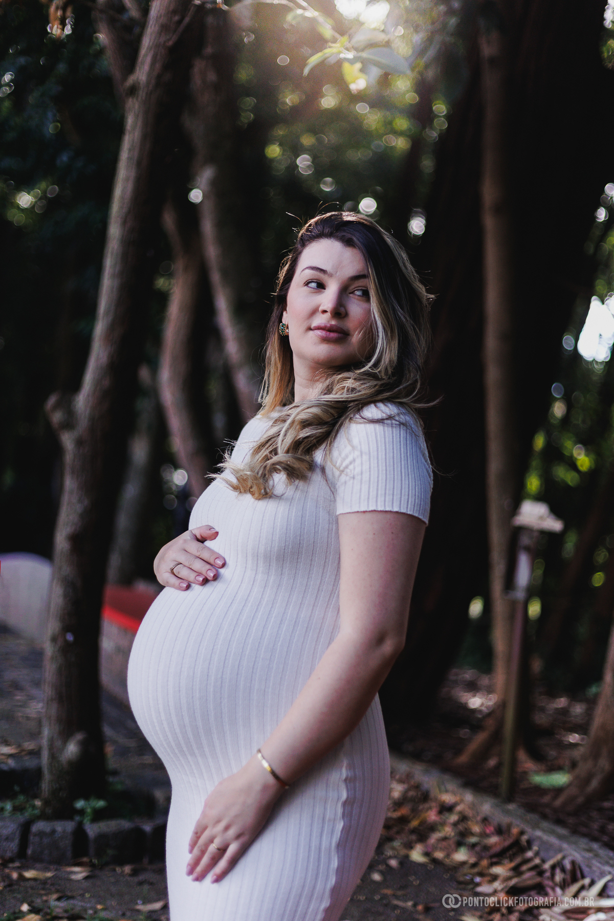 ensaio gestante em família em São Roque com luz natural entre árvores destacando a conexão e a espera do bebê John com fotografia suave e emocional ao ar livre
