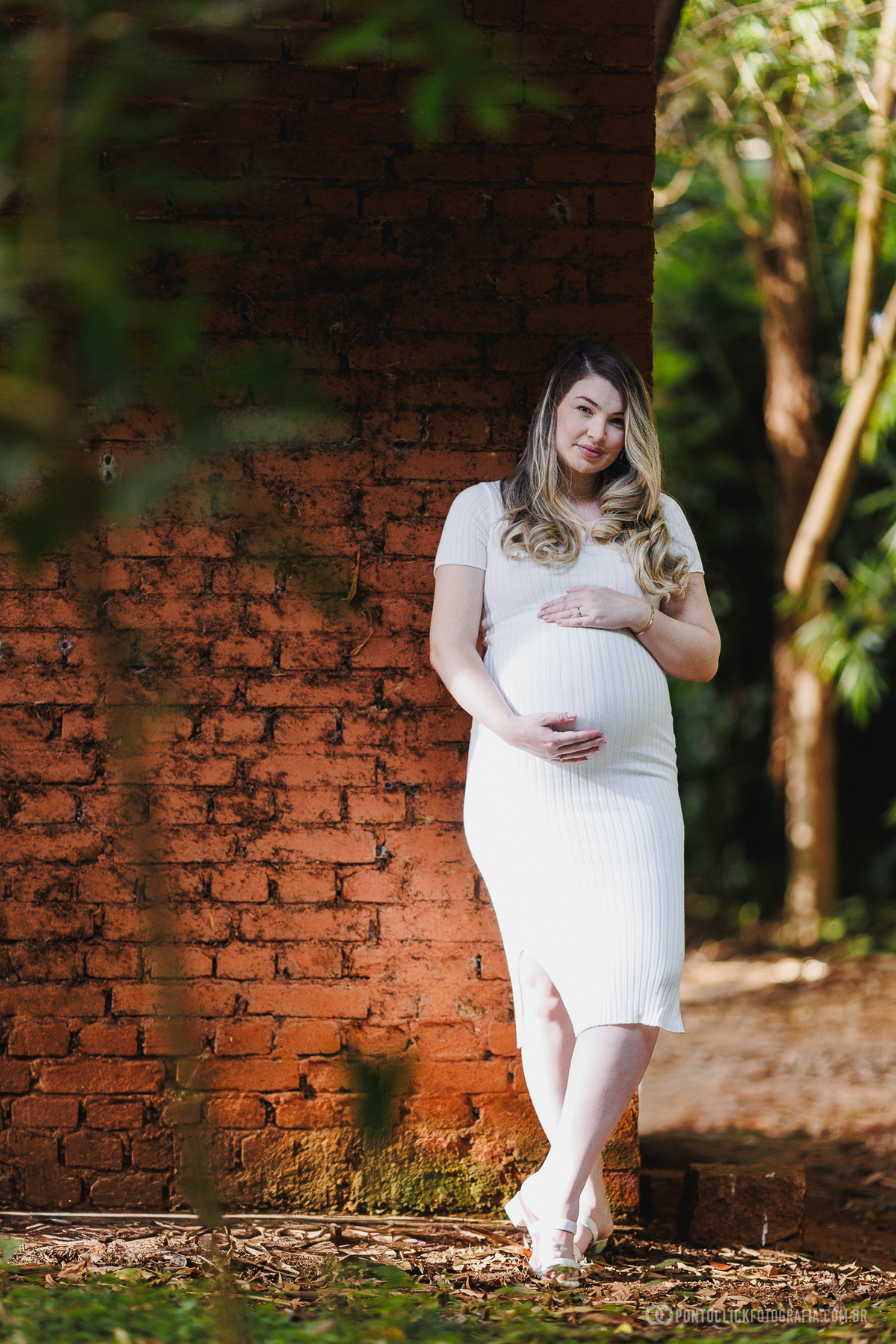 ensaio gestante natural com luz suave destacando a gestante em frente à parede rústica criando profundidade e estética elegante