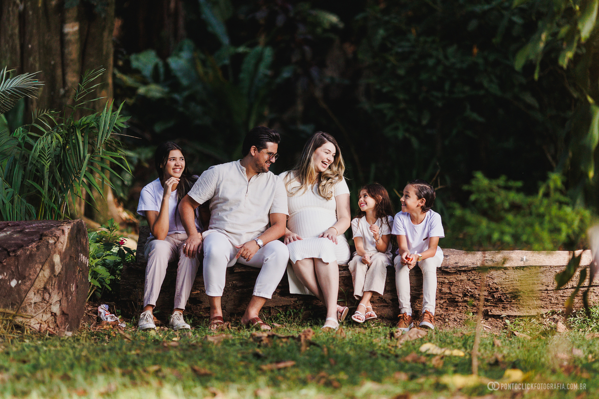 fotos de gestante em família sentados em ambiente natural mostrando conexão, alegria e a expectativa pela chegada do bebê John