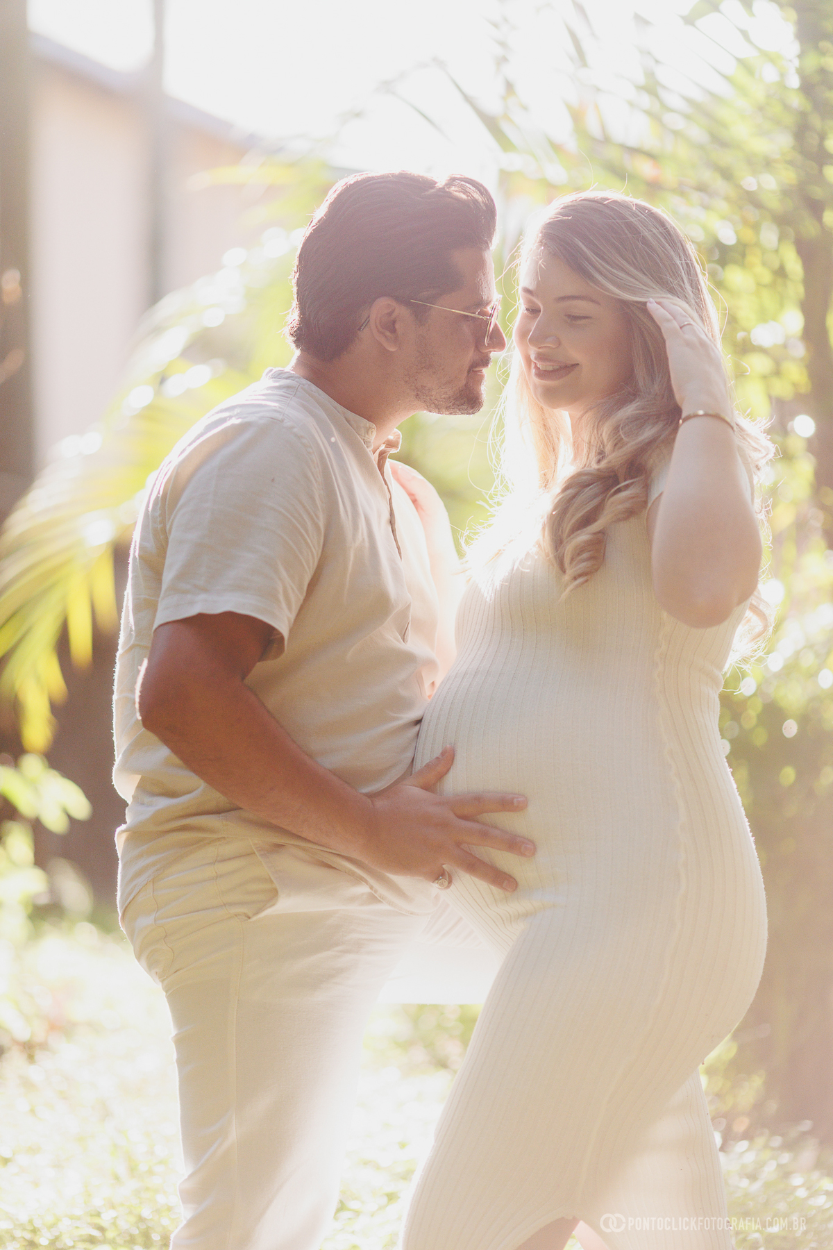 ensaio gestante casal com luz contra o sol criando efeito suave e romântico destacando a conexão e a espera do bebê John
