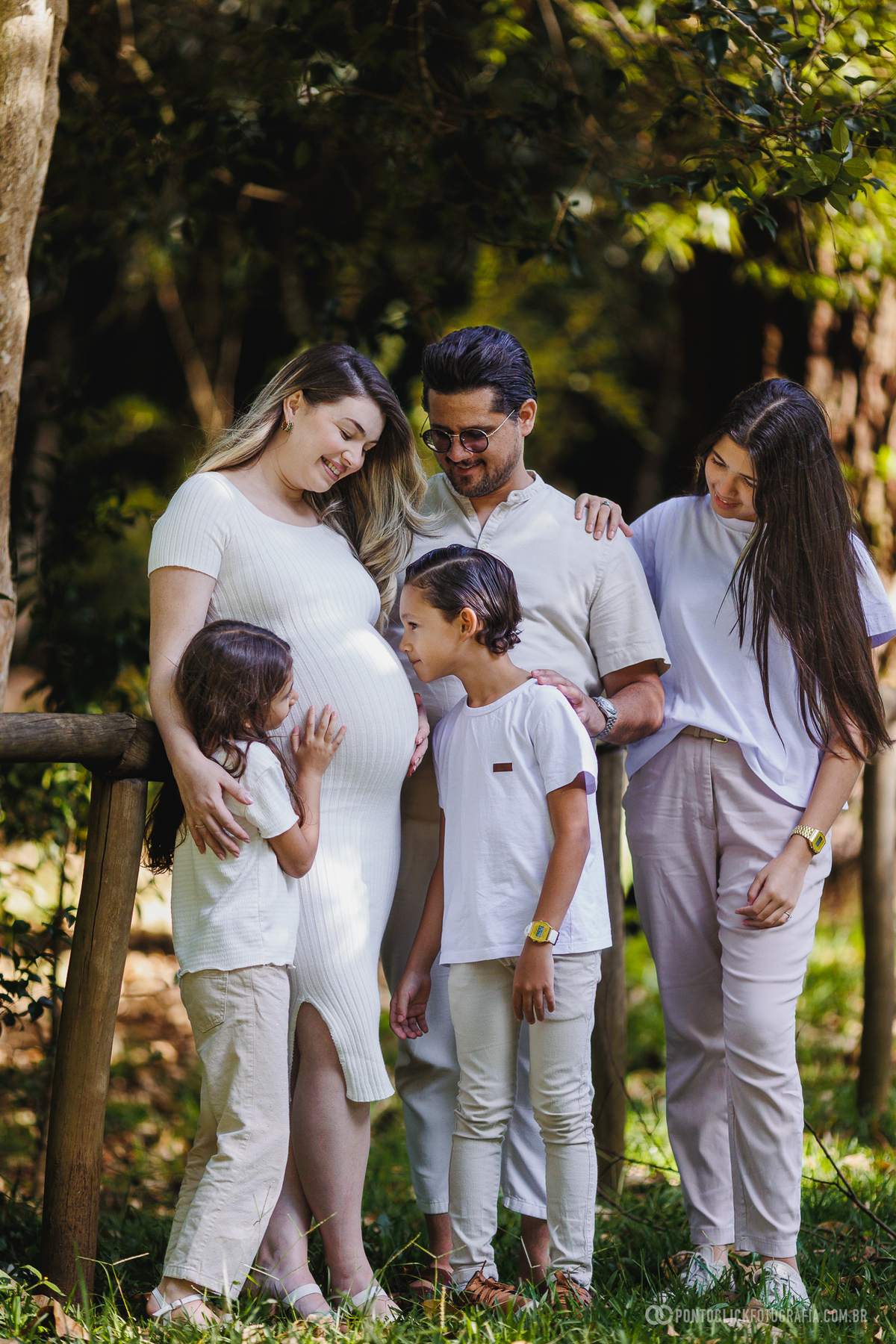 ensaio gestante em família em São Roque com luz natural entre árvores destacando a conexão e a espera do bebê John com fotografia suave e emocional ao ar livre