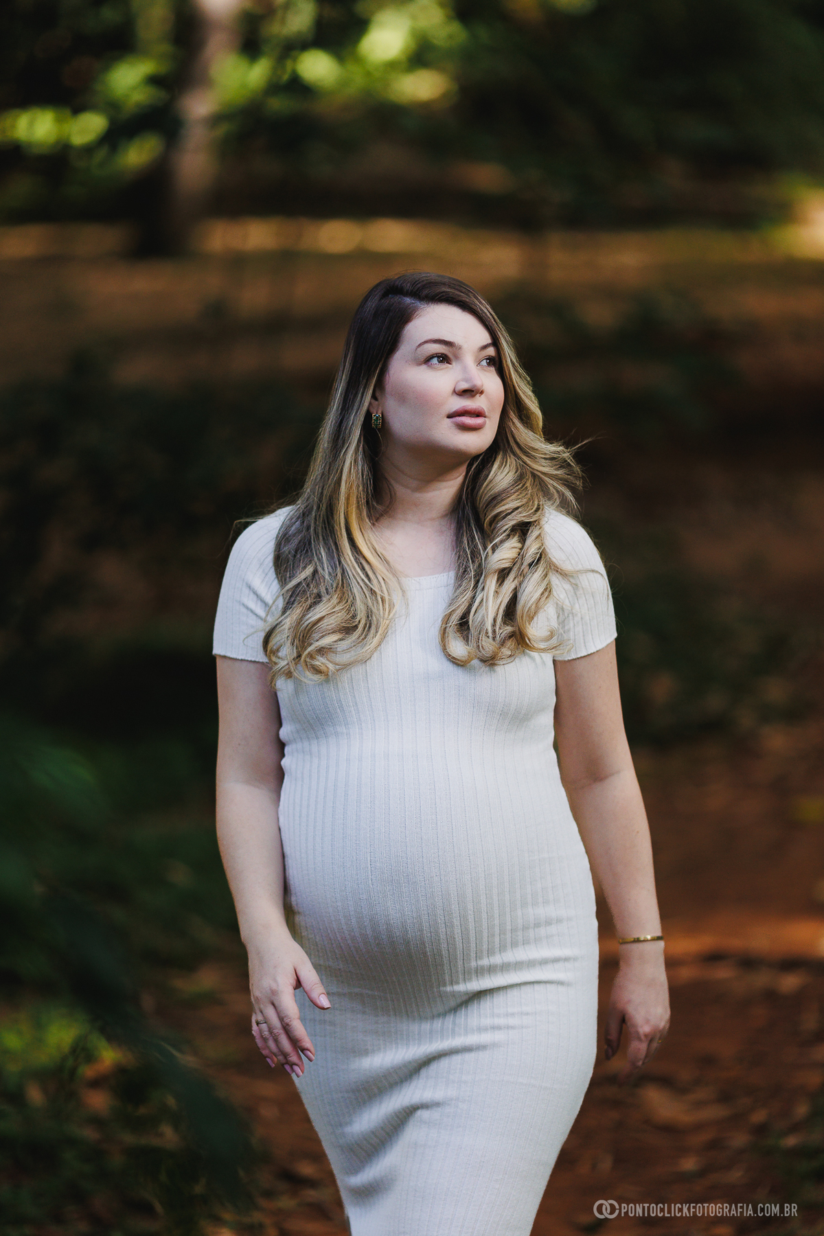 ensaio gestante natural com expressão contemplativa da gestante em ambiente externo valorizando luz, cores e emoção da maternidade