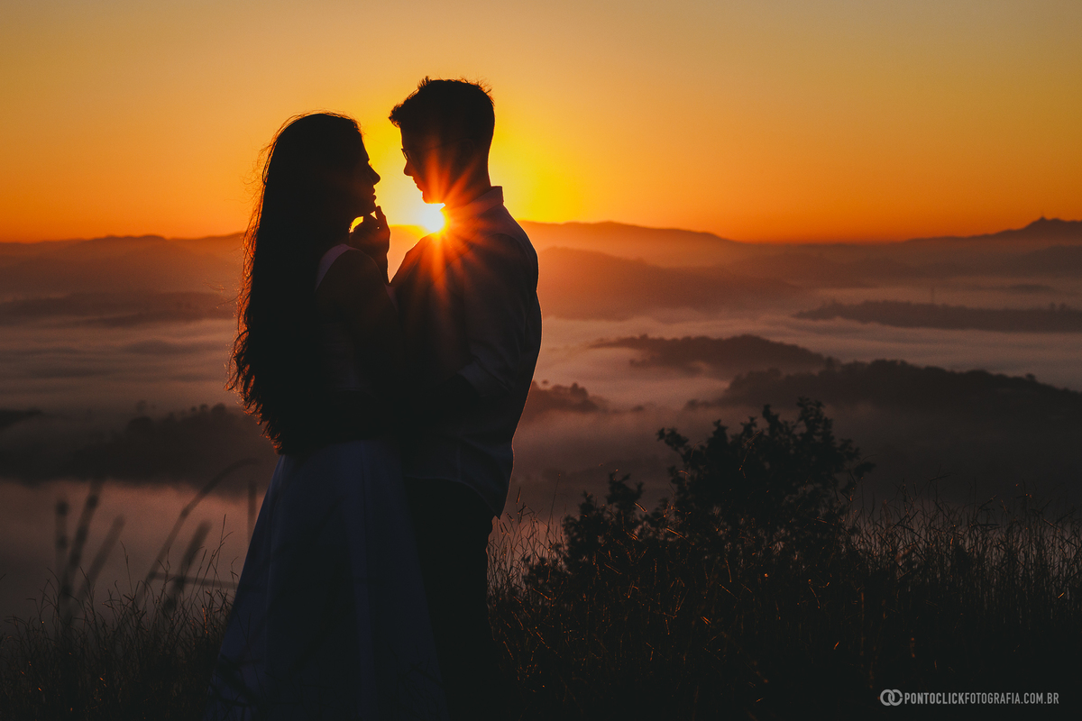 Casal em ensaio pré wedding no Morro do Capuava em Pirapora do Bom Jesus em silhueta com luz dourada ao fundo e mar de nuvens criando cenário romântico e cinematográfico